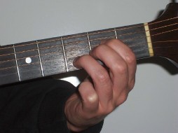 Picture of hand holding Asus4 in open on guitar